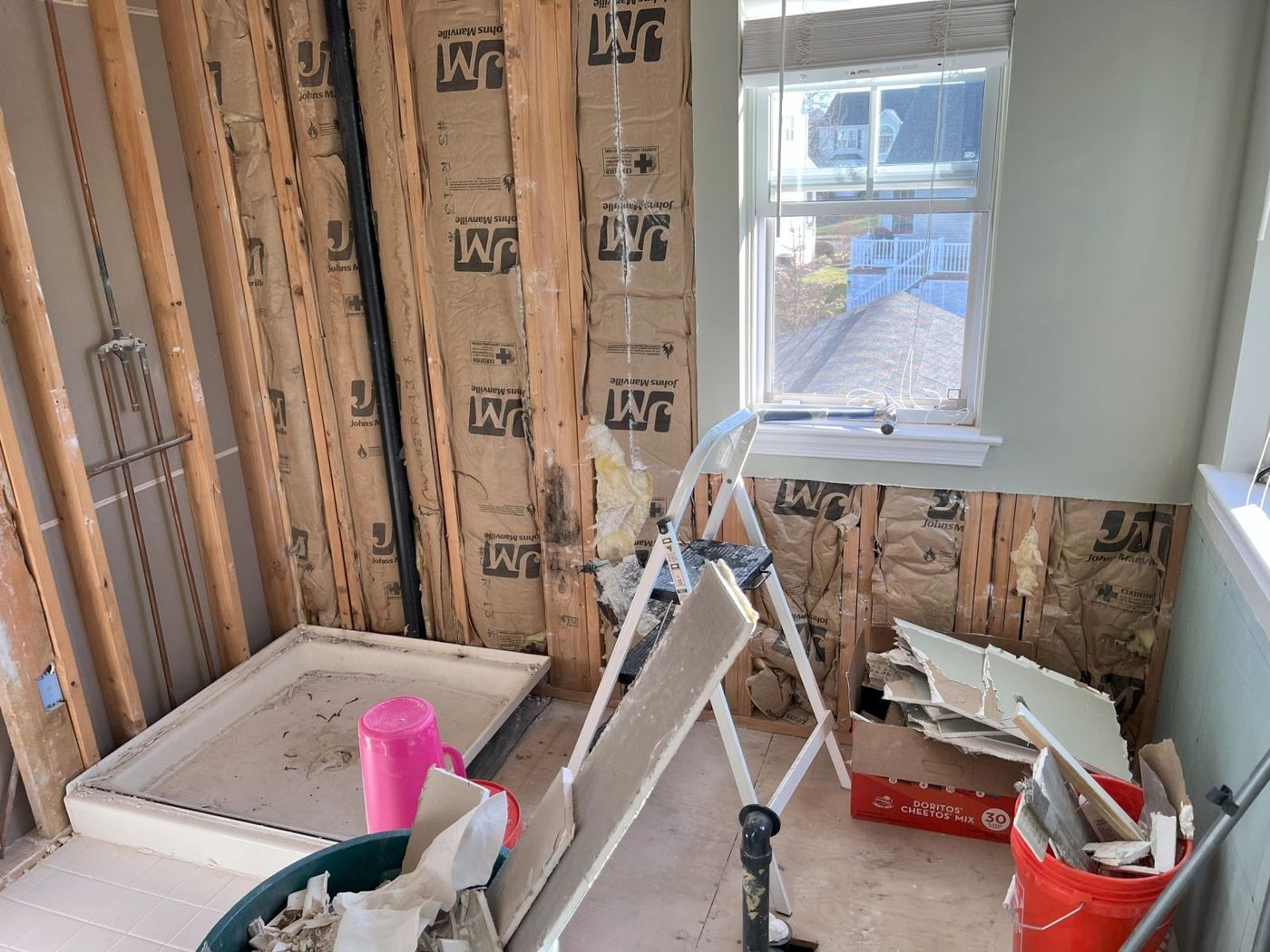 Bathroom stripped to the studs during demolition with a new shower pan set in place