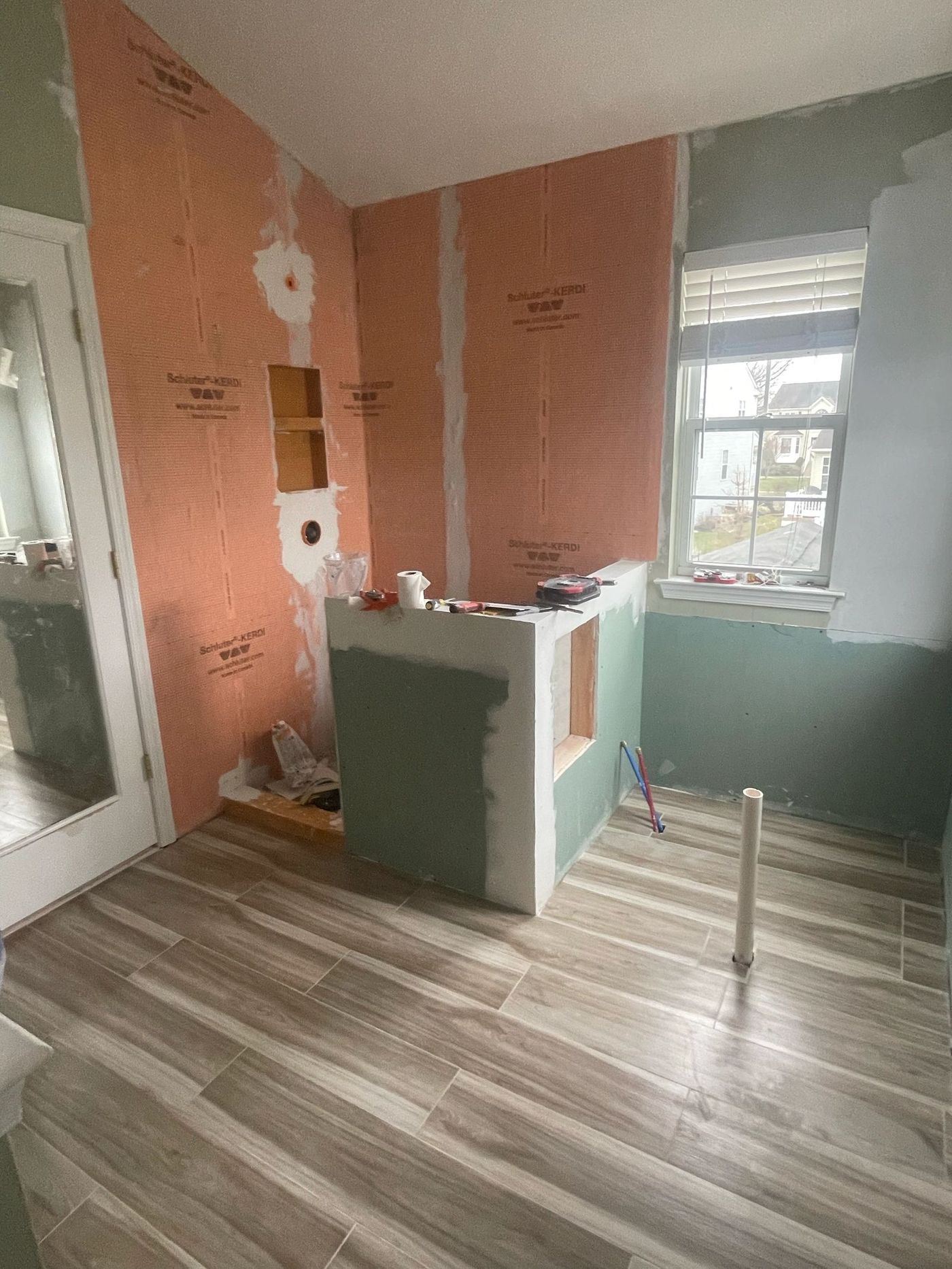 Room mid-remodel with framed knee wall, prepped walls and newly laid vinyl plank flooring