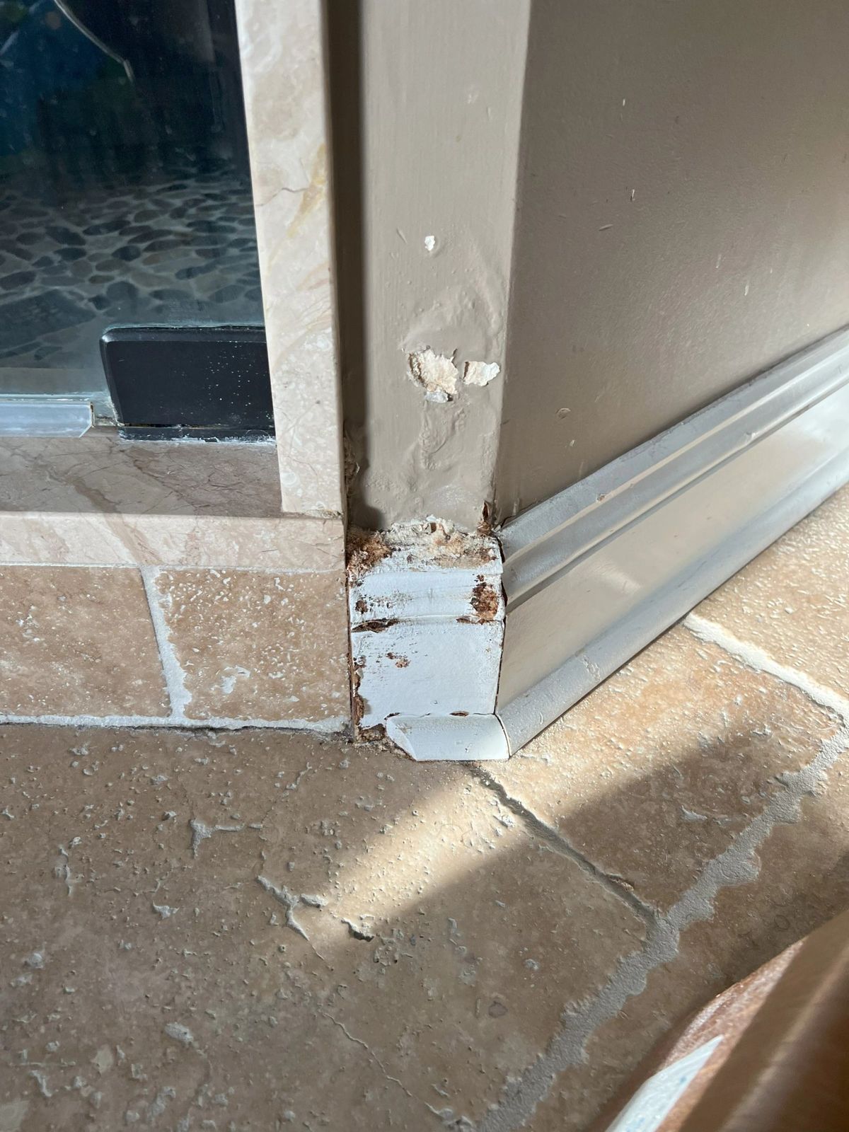 Before: rusted, peeling baseboard trim where it meets a stone tile floor